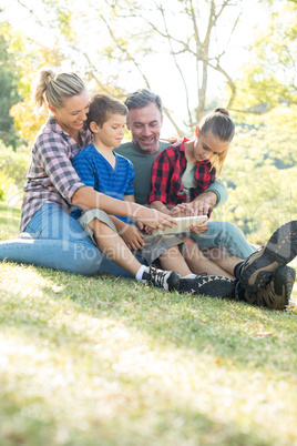 Family using digital tablet in the park