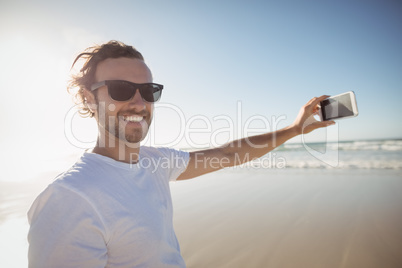 Portrait of smiling man taking selfie against clear sky at beach