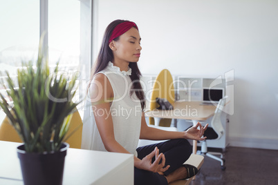 Young businesswoman doing yoga at office