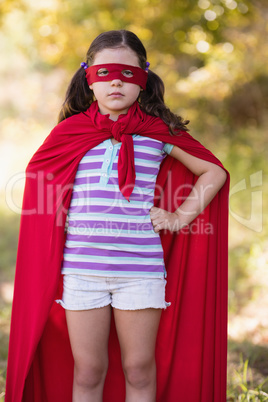 Confident little girl wearing superhero costume at campsite