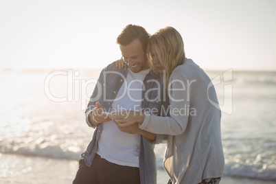 Happy couple using mobile phone at beach