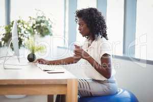 Executive sitting on fitness ball while working at desk