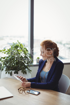 Beautiful executive using digital tablet at desk