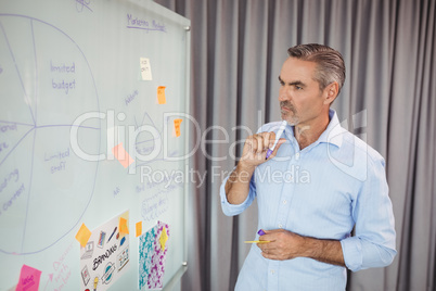 Thoughtful executive looking at figure on whiteboard