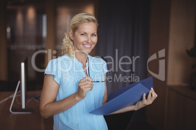 Portrait of smiling executive standing with file