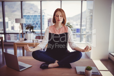 Beautiful executive meditating on desk