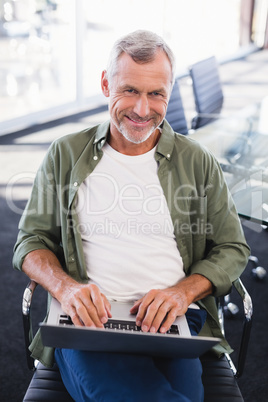 Portrait of smiling businessman using laptop