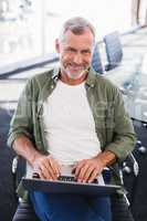 Portrait of smiling businessman using laptop