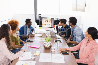 Colleagues looking at desktop pc while sitting at table