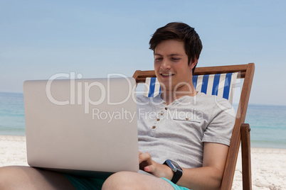 Man sitting on sunlounger and using laptop on the beach
