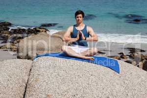 Man performing yoga on rock