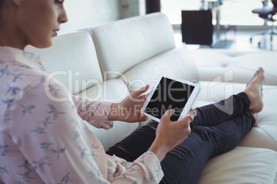Businesswoman using digital table while resting on sofa