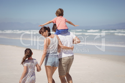 Rear view of happy family walking at beach