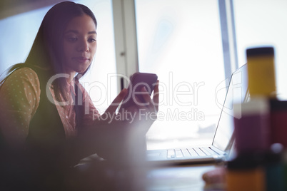 Businesswoman holding mobile phone at office