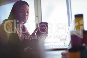 Businesswoman holding mobile phone at office