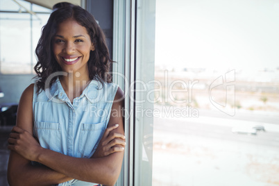Smiling businesswoman standing by window in office