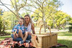 Daughter sitting on mothers lap while having picnic