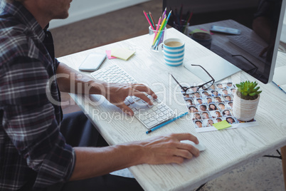 Male photographer using computer on desk in office
