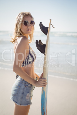 Portrait of beautiful woman holding surfboard at beach