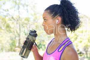 Female jogger drinking water in the park