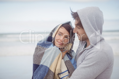 Man embracing her girlfriend wrapped in blanket during winter