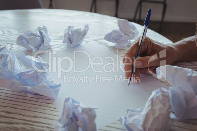 Businesswoman writing amidst crumpled papers on desk