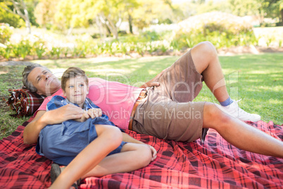 Father and son lying on picnic blanket in park