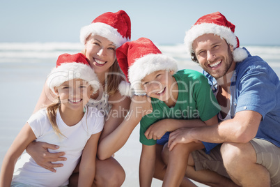 Portrait of happy family wearing Santa hat at beach