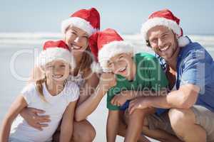 Portrait of happy family wearing Santa hat at beach