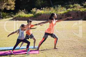 Female trainer with children practicing Virabhadrasana II pose