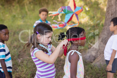 Little girl blindfolding friend at campsite