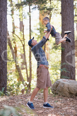 Father lifting son while hiking in forest