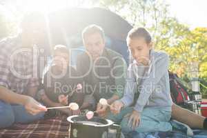 Family roasting marshmallows outside the tent