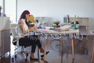 Young businesswoman working while sitting at desk in office