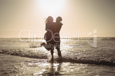 Silhouette couple enjoying on shore at beach