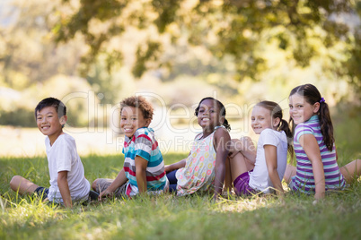 Smiling friends sitting on grass at campsit