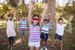 Friends with blindfolded girl cheering in forest