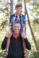 Happy father piggybacking son in forest