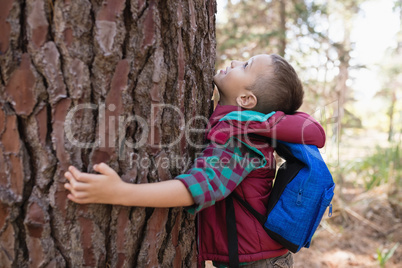 Side view of boy embracing tree