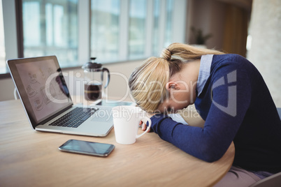 Tired businesswoman leaning on desk