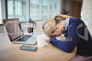 Tired businesswoman leaning on desk