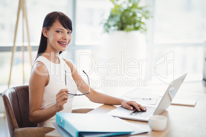 Portrait of smiling executive using laptop at desk