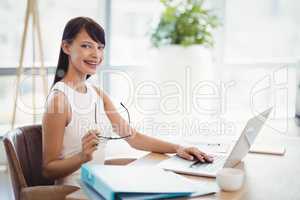 Portrait of smiling executive using laptop at desk