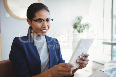 Smiling executive using digital tablet at desk