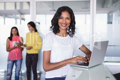 Portrait of smiling businesswoman using laptop