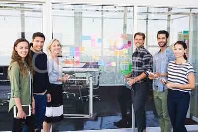 Portrait of business people standing by glass wall