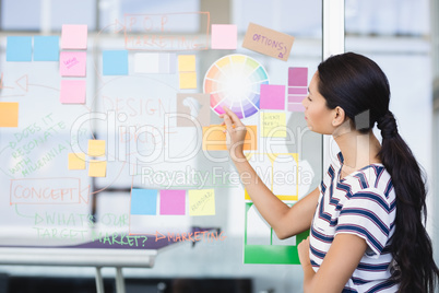 Businesswoman looking at plan on wall