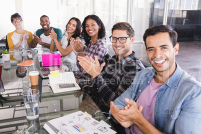 Portrait of business team clapping while sitting at creative office