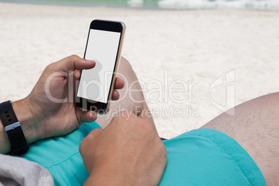 Mid section of man using mobile phone at beach