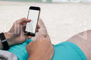 Mid section of man using mobile phone at beach